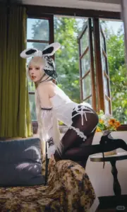 Bên khung cửa nắng dịu, cô nàng tóc bạc ngồi nghiêng trong bộ đồ cosplay tai thỏ