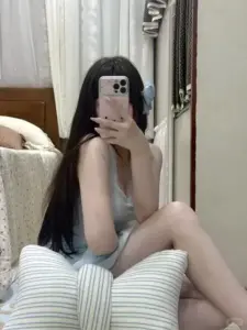Bên giường nàng xinh ngồi co chân dùng điện thoại giấu biểu cảm trước gương sáng