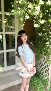 Bên khung cửa phủ dây leo, cô gái áo xanh nhạt váy trắng mỉm cười dịu