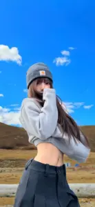 Áo hoodie xám, mũ lưỡi trai và bầu trời xanh tạo vẻ năng động cho cô gái