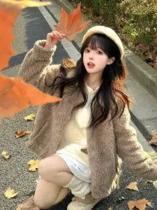 Áo khoác lông be làm nàng thêm mềm khi ngồi giữa lá thu, tay cầm lá cam