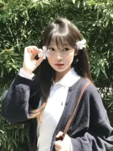 Tóc mái thưa phủ nhẹ trán, nàng mặc cardigan đen và nâng bông hoa trắng bên má