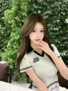 Góc chụp ngoài trời làm nổi bật cô gái áo polo kem, tóc nâu dài và ánh mắt mềm