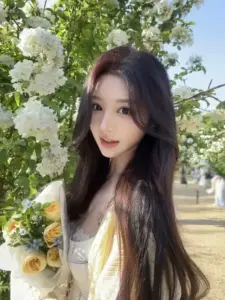 Cô nàng tóc dài đứng cạnh giàn hoa trắng, mặc áo vàng nhạt với ánh nhìn trong veo