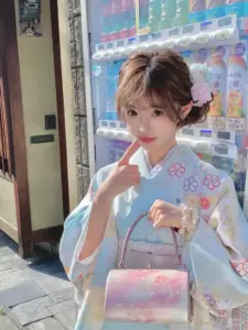 Trên con phố truyền thống, cô gái mặc kimono xanh cầm túi pastel, nụ cười tươi tắn