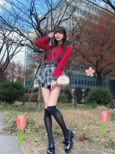 Cô nàng áo len đỏ tạo dáng bên hàng tulip, tóc đen dài và váy caro nổi bật