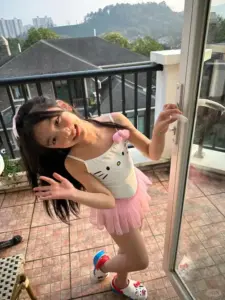 Ảnh gái xinh Trung Quốc áo trắng quần hồng cúi người vui vẻ trên ban công nắng