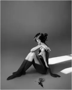 Dáng ngồi co gối bên tường xám tạo cảm giác lặng, nude nghệ thuật và mềm mại