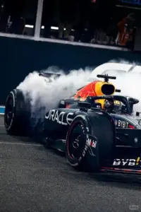 Làn khói trắng cuộn sau bánh sau, xe Red Bull tăng tốc mạnh trên nền đường tối.