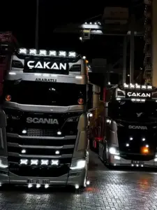 Chiếc MAN TGX màu đỏ đứng trước kho hàng, thùng sau xếp thẳng với vạch kẻ nền.