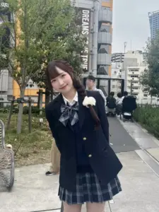 Dọc vỉa hè thành phố, nữ sinh mặc blazer đen cười nghiêng, tóc nâu xõa mềm tự nhiên