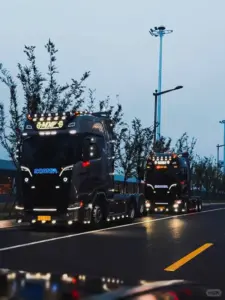 Đầu kéo container màu bạc chạy thẳng trên cao tốc, ánh nắng sớm phủ lên kính chắn gió.