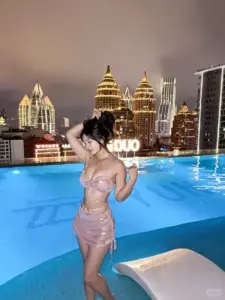 Đêm bên hồ khách sạn, cô gái quấn khăn hồng nhạt tạo dáng nghiêng, tóc búi cao