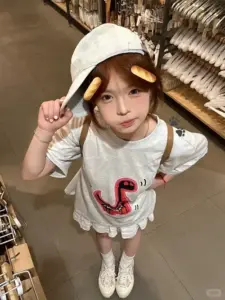 Mũ lưỡi trai trắng đỏ che nhẹ trán, nàng áo trắng tạo dáng từ góc nhìn cao
