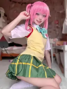 Mái tóc hồng rực và váy xanh tạo nên tạo hình anime tươi vui bên phông nền sân khấu