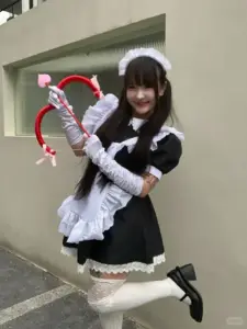 Tường xám ngoài trời nổi bật cô nàng cười tươi, váy maid xanh đen và găng trắng
