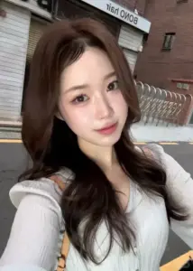 Lúc selfie trong áo cardigan trắng, cô gái để tóc xoăn nâu và làn da sáng hồng