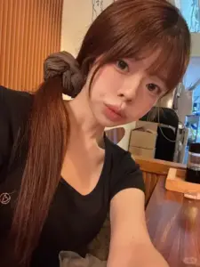 Với tóc buộc hai bên, nàng mặc áo đen ở quán cà phê, biểu cảm dễ thương