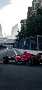 Giữa phố hẹp, xe Ferrari đỏ chạy sát mép đường, bóng cây che dọc khúc cua.