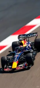 Xe Red Bull ôm sát lề đỏ trắng, thân xe nghiêng nhẹ trong khúc cua tốc độ cao.