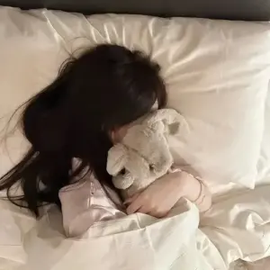 Chiếc giường trắng ôm gương mặt khuất của cô gái tóc nâu, tay ôm gối rất mềm