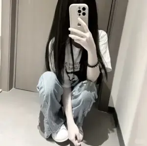 Nền tường trắng làm cô nàng ngồi bệt trước gương, áo trắng và quần bò sáng nổi bật