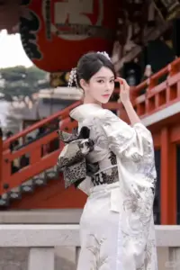 Bên cây cầu đỏ, cô gái mặc kimono trắng tạo dáng nghiêng, tóc búi gọn thanh thoát