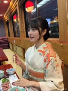 Trong quán ăn kiểu Nhật, hot girl Nhật mặc kimono cam trắng ngồi cười, tóc ngắn đáng yêu