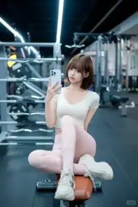 Trong phòng gym, bạn gái mặc áo trắng tạo dáng ngồi với thần thái khỏe khoắn và tự tin