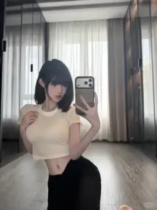 Outfit áo croptop trắng làm bóng hồng tóc ngắn tạo dáng trước rèm trông rất gọn mắt