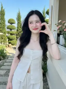 Ngoài khu vườn tỉa cây, cô nàng Việt áo trắng chạm má, cười hiền dưới nắng trong