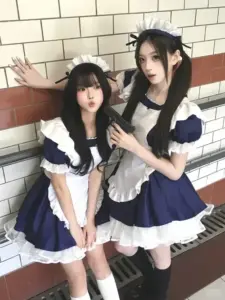 Hai cô nàng đứng cạnh tường gạch, mặc váy maid xanh trắng với mái tóc đen dài