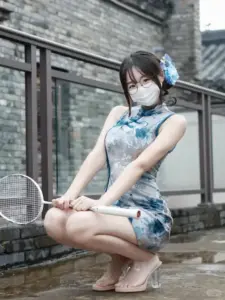 Bên tường gạch xám, một nhan sắc Á Đông mặc váy xanh hoa ngồi xổm rất duyên