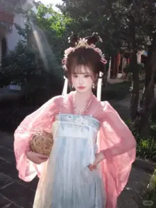 Ảnh gái xinh Trung Quốc mặc hanfu hồng đứng trong vườn cây, tay ôm giỏ hoa