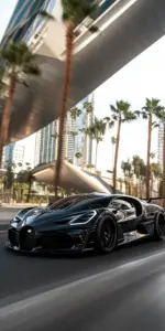 Chiếc Pagani bạc nằm giữa nền đá xám, phía xa là Bugatti đen phản chiếu ánh đèn.