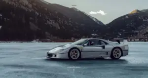 Bánh xe đen đứng trên mặt đường nhựa ướt, vệt đèn vàng loang nhẹ quanh lốp trước.