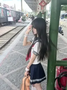 Ở lối băng qua đường, cô bạn đồng phục quay nghiêng, tóc dài bay nhẹ trong nắng phố