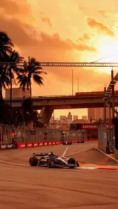 Thân xe đỏ bóng của Ferrari SF-24 lao vụt qua đoạn thẳng, bánh xe mờ nhoè và khán đài phía sau rực nắng.