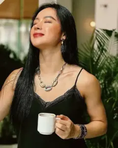 Ly trắng trên tay đi cùng nụ cười thoải mái, áo đen nổi bật bờ vai săn