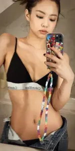 Cô gái chụp selfie gương với áo tắm đen, búi tóc và dây điện thoại nổi bật