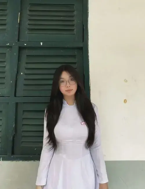 Nữ sinh cấp 3 xinh xắn trong bộ đồng phục trắng, tóc thả nhẹ và nụ cười rất hiền