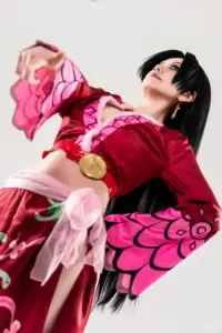 Coser hóa thân Reiju tựa lưng bên tường hồng, trang phục ôm gọn và thần thái sang lạnh