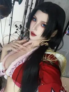 Coser nữ cosplay Tashigi với kính tròn, thanh kiếm trên tay và vẻ nghiêm túc rất dễ nhận ra