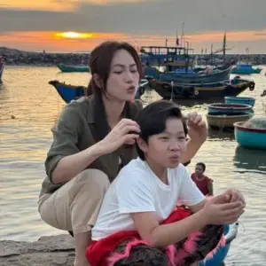 Bên bến thuyền hoàng hôn, nữ diễn viên buộc tóc cho bé trai, nét mặt tập trung