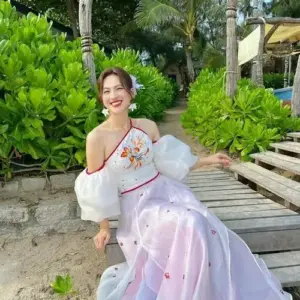 Dáng ngồi váy trắng hoa bên lối gỗ nhiệt đới khiến nụ cười cô sáng hơn