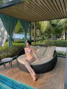 Dưới mái hiên resort, người đẹp ngồi trên ghế mây với bikini tím pastel mềm mắt