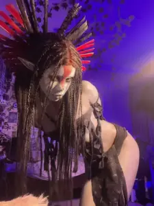 Người mẫu cosplay anime tóc bạc đứng cạnh tường kính, bikini xanh biển làm khung hình thêm mát mắt