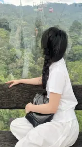 Bên sườn đồi mờ sương, cô gái ngồi trên đá với áo trắng và tóc buộc