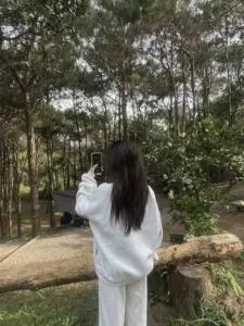 Gái giấu mặt đứng giữa rừng thông, bộ đồ trắng rộng khiến dáng chụp thêm trong trẻo