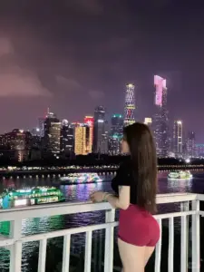 Dưới ánh đèn thành phố ban đêm, người đẹp váy hồng đứng tựa lan can với dáng mông cong rõ